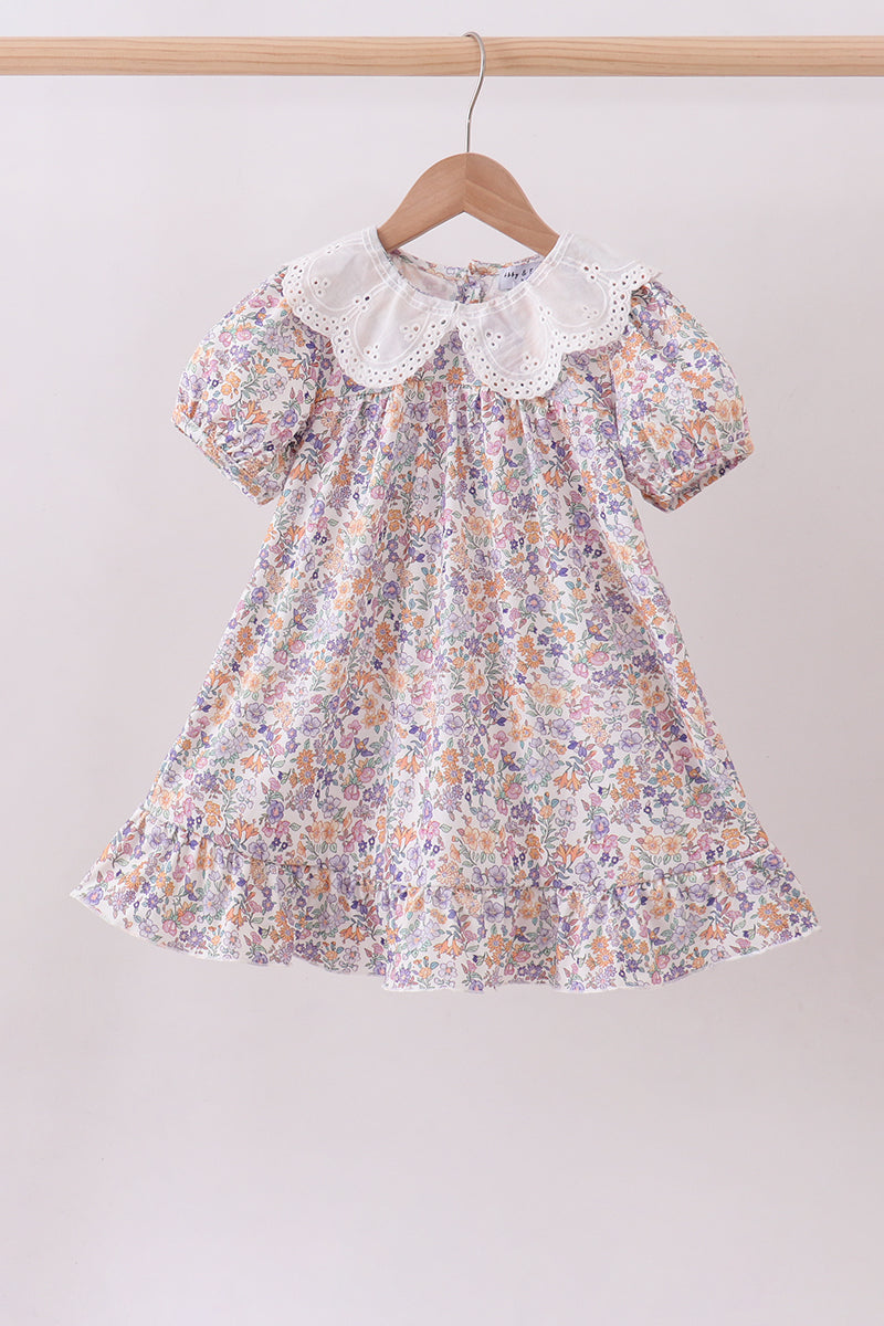 Floral dress with a lace collar on a hanger against a plain background