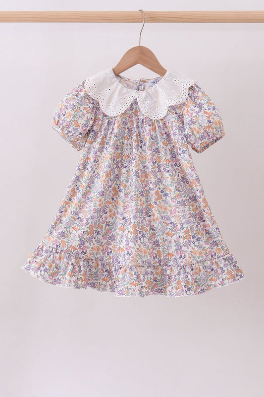 Floral dress with a lace collar on a hanger against a plain background